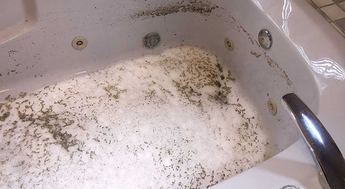 Dirty jetted tub with black flakes